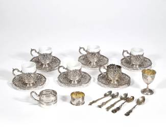 (20pc) CONTINENTAL SILVER DEMITASSE & ACCOUTREMENTS | 800 silver, including a set of 6 demitasse cup surrounds with repousse decoration of putti on reserves (one missing porcelain insert weighing 1.89 ozt, all together approx. 11.34 ozt), 6 matching openwork saucers, an openwork garland pattern demitasse surround, 5 demitasse spoons (two with rose handles, two with beasts, one with putti), and a small goblet with gilt interior and matching napkin ring; total approx. silver weight 26.7 ozt
 - w. 2.75 x h. 2.5 in. (each)