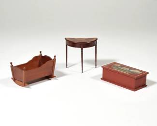(3pc) SIGNED DOLLHOUSE FURNITURE | Miniature dollhouse furniture, including a 19th century painted chest decorated with a clipper ship, with inscription on bottom, "hand painted by Janet Babley great grand daughter of Andrew Jackson 2nd Mate on the Charles W Morgan Voyage #9 Sept. 26 1871 to Oct 31, 1874" [hinged lid detached]; a cradle signed and dated '87, and a demilune console table with inlay, signed and dated 1989.
