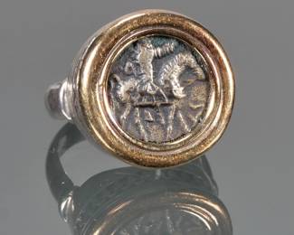 ANCIENT COIN, 14K GOLD, & STERLING SILVER RING | Designed as a central Roman or Greek ancient coin showing a figure on horseback within a 14k yellow gold surround and mounted on a sterling silver ring; size 6, total weight 9.6g.

