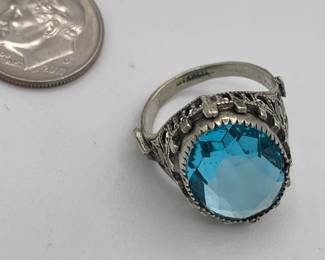 Closeup of sterling silver ring with blue stone, possibly topaz