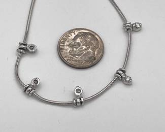 Closeup of 14k white gold serpentine necklace with 5 pendant diamond spacers, made in Italy