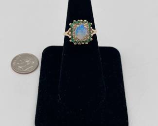 10k gold ring with central opal surrounded by stepped row of diamonds and emeralds