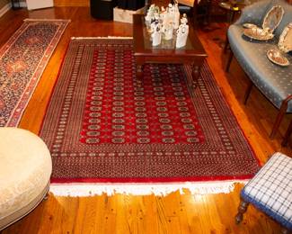 Large area rug in glowing colors, along with a runner, stylish sofa, comfortable chairs with ottomans, silver plate and collectibles