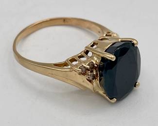 Closeup of 14k gold ring with large very dark sapphire and small side diamonds