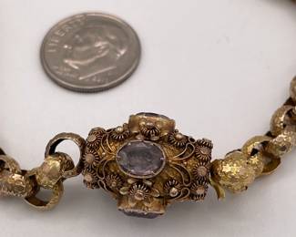 Closeup of 19th Century pinchbeck guard chain / necklace with textured round links and an elaborate barrel clasp with cannetille embellishment and set with amethysts