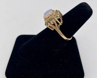 10k gold ring with central opal surrounded by stepped row of diamonds and emeralds