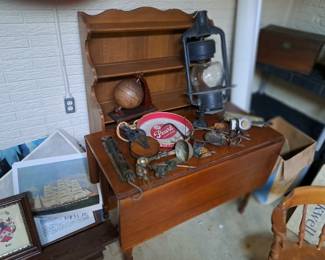 Antique cherry drop leaf table with primitives & Dietz railroad lantern on top, open shelf cupboard at rear.