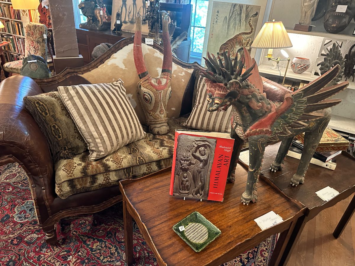 Early 20th century large painted wood sculpture. Wonderful leather sofa with hide tufted back and saddle blanket upholstery cushion. pair of 2 Minton Spidell tables. Wooden carved Indian Nandi head. 