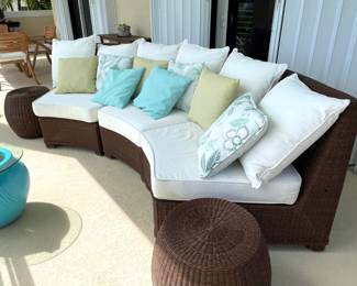 Three-piece wicker curved outdoor couch with cushions, pillows and round endtables