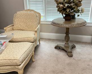 French Provincial style Bergere chair and ottoman, pedestal table, large flower arrangement.