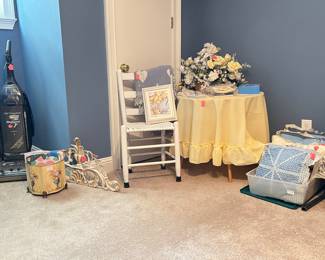 White wooden ladder-back chair with woven seat, display table, pillows, Hoover WindTunnel vacuum, floral arrangement, smalls...