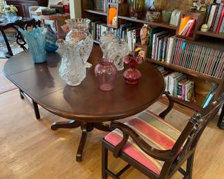 Single pedestal dining table with leaf and 2 armchairs, and large crystal and blown glasses vases