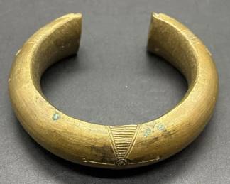 Antique African Engraved Brass Currency Bracelet. This piece, along with several other African artifacts comes from an estate in the Atlanta, GA area. We do not know anything about its origin as it was found behind hidden within the walls of an old home that was being torn down. The bracelet has intricate engravings as shown and it weighs in at 7.9 Oz. It is approx 3” in diameter and it is a approx .75” thick at its thickest point as shown.