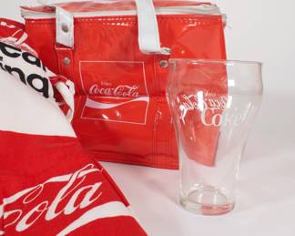 Closeup of Coca Cola brand merchandise including plastic cooler, shorts, pants, glasses, coasters, bottle crate