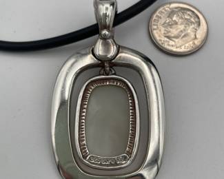 Closeup of sterling silver and mother of pearl modernist pendant on cord necklace with sterling clasp