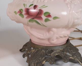 Closeup of base on antique glass lion head rose hurricane lamp on ornate metal base, converted to electricity