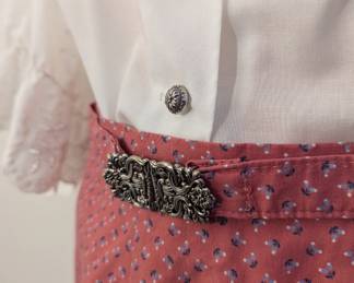 Closeup of women's white blouse with lace sleeves and belted skirt