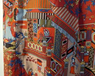 Closeup of vintage Asian style sleeveless dress with fabric frog button closure at throat, bright fabric depicting modernist interpretation of courtyard and interior scenes 