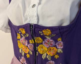 Closeup of women's German dirndl dress, embroidered, purple, with apron
