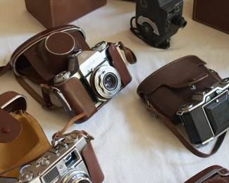 Another closeup of vintage cameras and leather cases including Paxette, Agfa, Bell & Howell, Canon, and Zeiss Ikon
