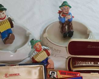 Closeup of Hohner harmonicas, melodicas, German figural ashtrays, tie tacks/pins