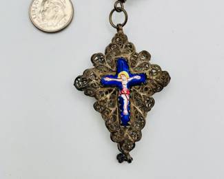 Closeup of filigree silver necklace with figural beads and religious pendant with enameled crucifix