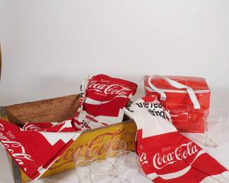 Coca Cola brand merchandise including plastic cooler, shorts, pants, glasses, coasters, bottle crate