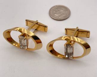 Pair of cufflinks in gold tone metal, oval bands holding clear emerald cut stones