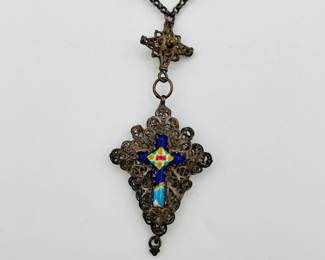 Closeup of filigree silver necklace with figural beads and religious pendant with enameled crucifix