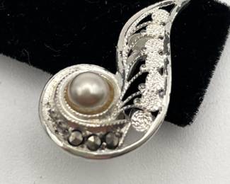 Closeup of pair of silver (835) filigree earrings with pearl