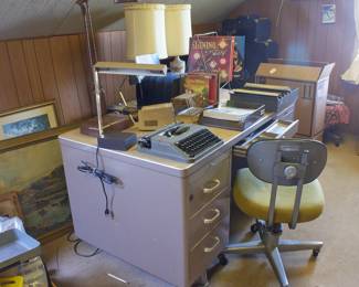 Metal desk, typewriter, desk lamp, filing materials, padded office chair on wheels