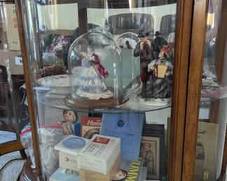 Curved glass display cabinet; Dresden porcelain figrine, Hummel figurines and collectors' books