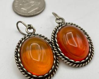 Closeup of pair of amber earrings, oval cabochon amber in rope-style silver border