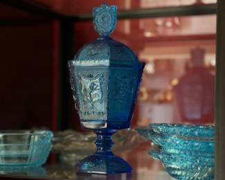This is a vibrant blue glass compote featuring embossed astrological symbols and a distinctive "G" logo with a crown, likely indicating its origin from Guernsey Glass.