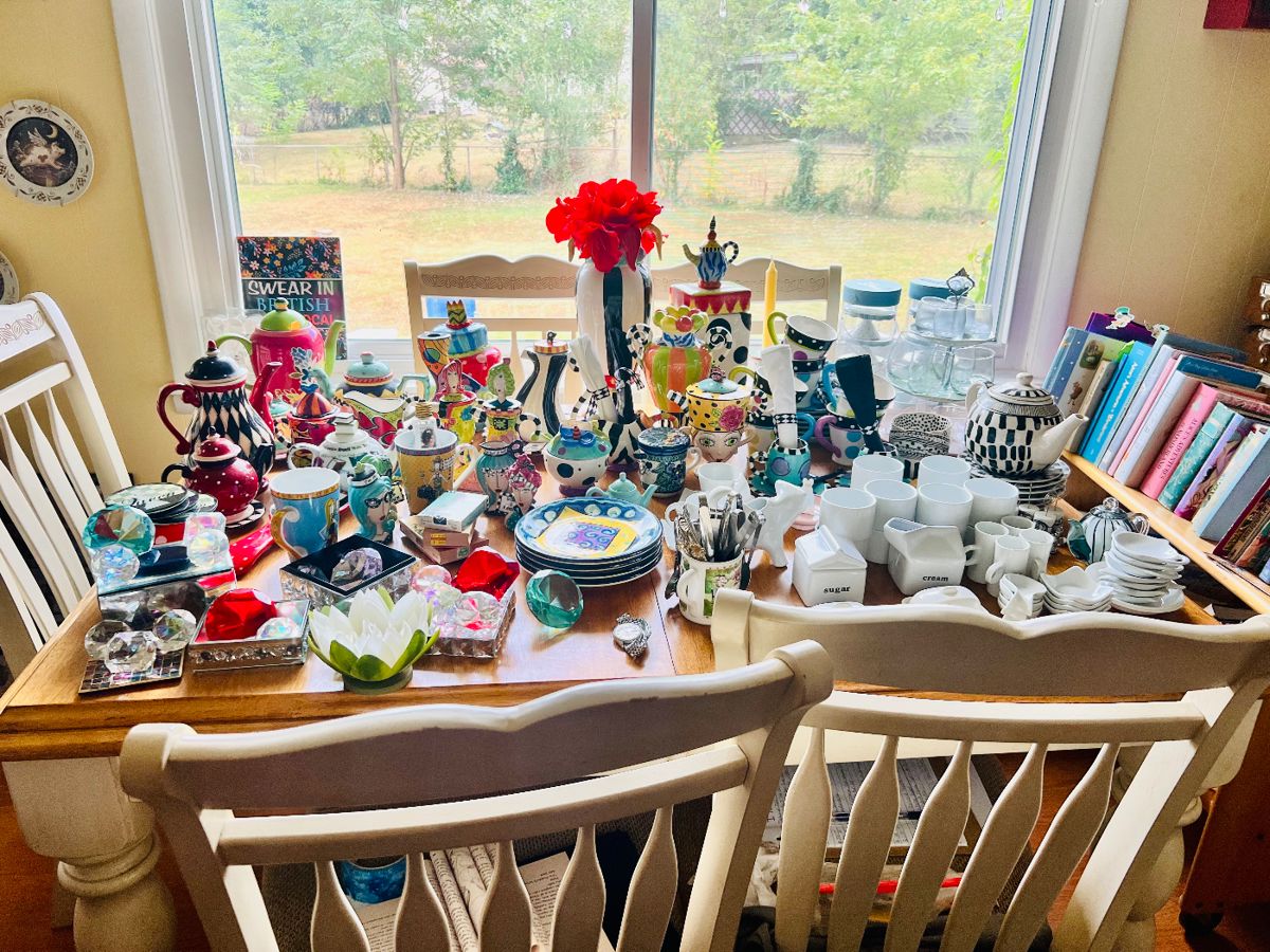 Ashley Furniture Dining table with 6 chairs and bench. Collector’s dishes, tea pots, Artist signed Gems, Library Cart filled with Alice in Wonderland Books, and so much more