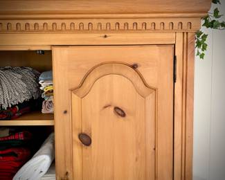 Pine armoire filled with linens (tablecloths, runners, napkins, and placemats) and fabric remnants