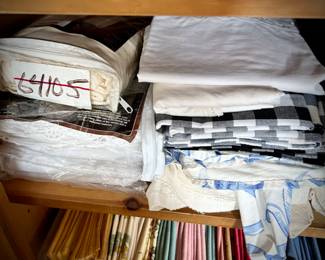 Pine armoire filled with linens (tablecloths, runners, napkins, and placemats) and fabric remnants