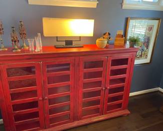 Tall console Cabinet with finished back, wood shelf inside and glass fronted doors; black brass double banker's light, Waterford bud vases, and brass beaded candle holders