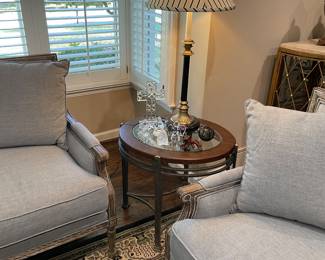 Round side table with leather trim and glass top with metal base, black and gold table lamp and crystal figurines (Swarovski, Simon Pierce, and Waterford) shown next two matched set of 2-cushion sofas