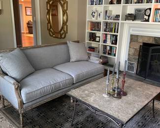 Another view of the 2-cushion couch, cocktail table, 100% wool area rug, metal candle holders, and large gold mirror