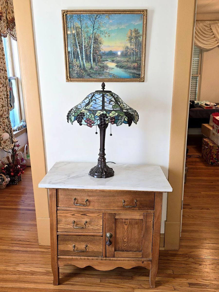 Antique oak dry sink with marble top. Tiffany style stained glass lamp. Vintage art print