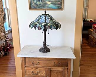 Antique oak dry sink with marble top. Tiffany style stained glass lamp. Vintage art print