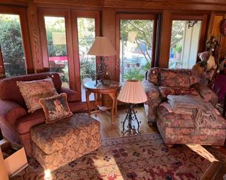 You can see the two lamps, the round side table, and the two overstuffed chairs with footrests.