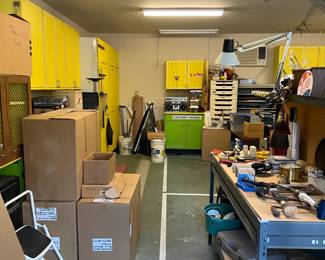 The garage has a large workshop area with lots of cabinets in yellow and green.  