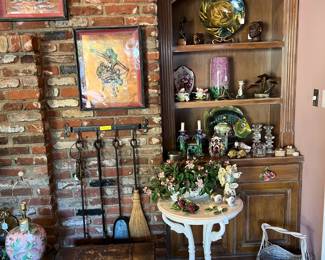 It's a bit invisible in this picture, but there is a trunk on the floor (bottom left), between the vase and the round, white table.  Fireplace tools are hanging on the brickwork, too.