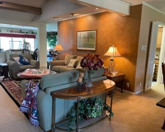 Looking across the living room, sofa/entrance table, faux plants, metal base lamps