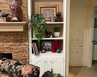 This shelf has more books, floral pottery and art