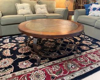 Round coffee table with stone top and metal legs and shelf, black/white/red rug