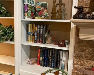 This book shelf has lots of John Grisham books, metal accent pieces, book ends