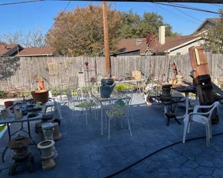 Outside lots of yard art, corner shaped bakers rack, metal shelves, picnic table, chairs, metal table with chairs, vintage metal lantern